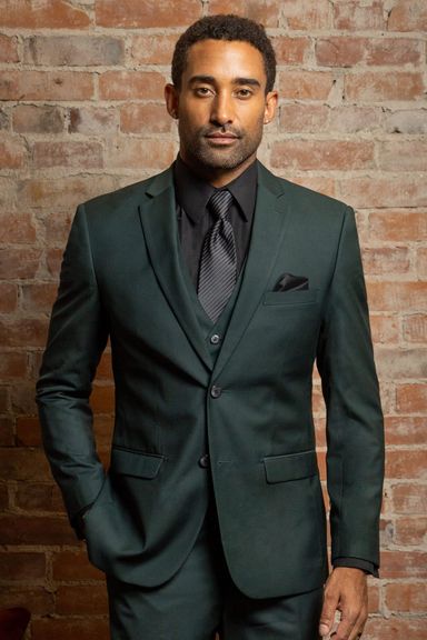 Man wearing a dark green formal suit with a black shirt and tie