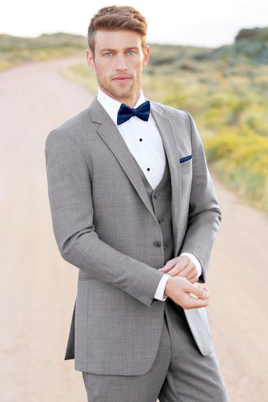 Man wearing a light grey three-piece suit with a navy bow tie