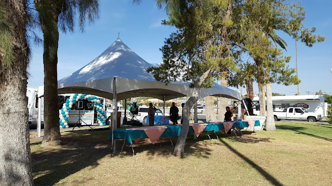 Large white event tent filled with rows of banquet tables, green linens and white folding chairs from Pizazz Rents & Events in Bullhead City
